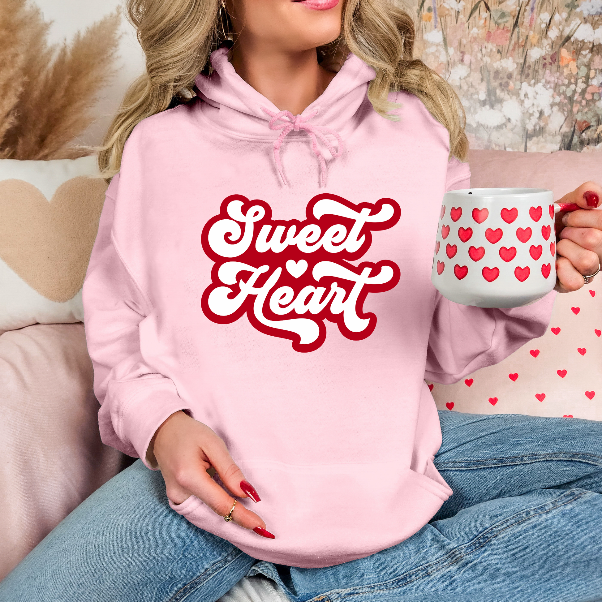 Front view of a girl wearing a pink hoodie with sweet heart written in Red letters