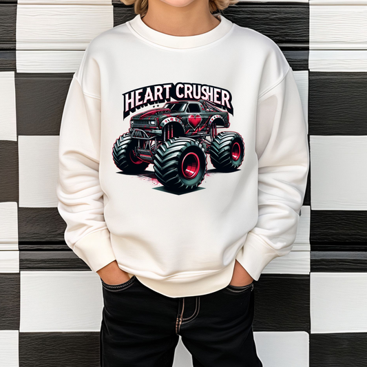 A child wearing a white monster truck sweatshirt with 'Heart Crusher' text and heart graphics on the front, standing against a checkered background.