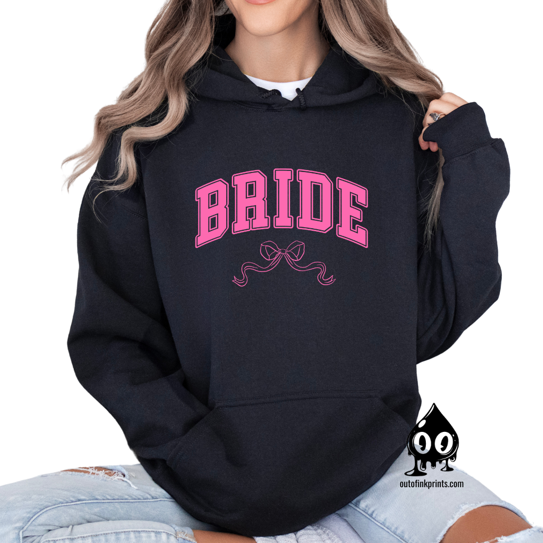 A woman wearing a black hoodie with the word 'Bride' and a pink bow printed on the front.