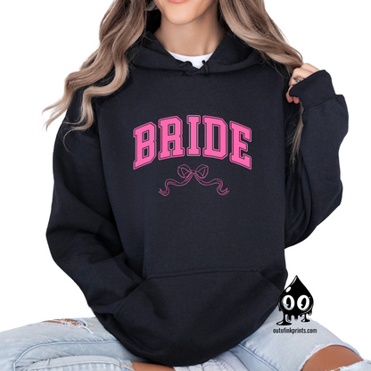 A woman wearing a black hoodie with the word 'Bride' and a pink bow printed on the front.
