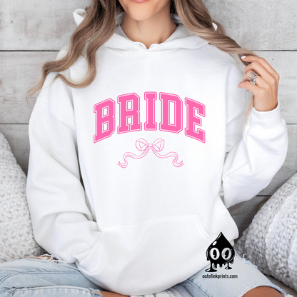 A woman wearing a white hoodie with the word 'Bride' and a pink bow printed on the front.