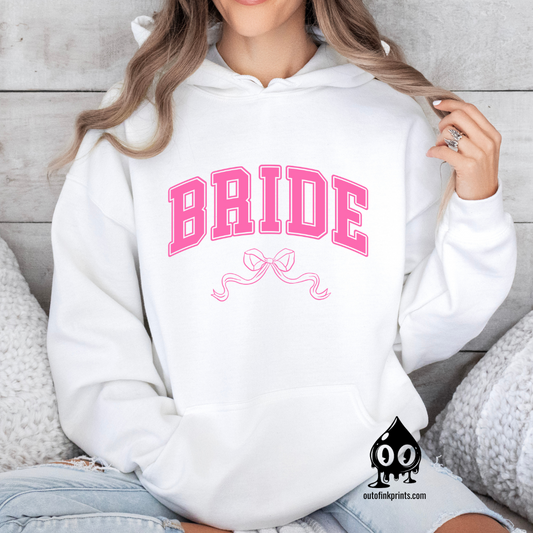 A woman wearing a white hoodie with the word 'Bride' and a pink bow printed on the front.