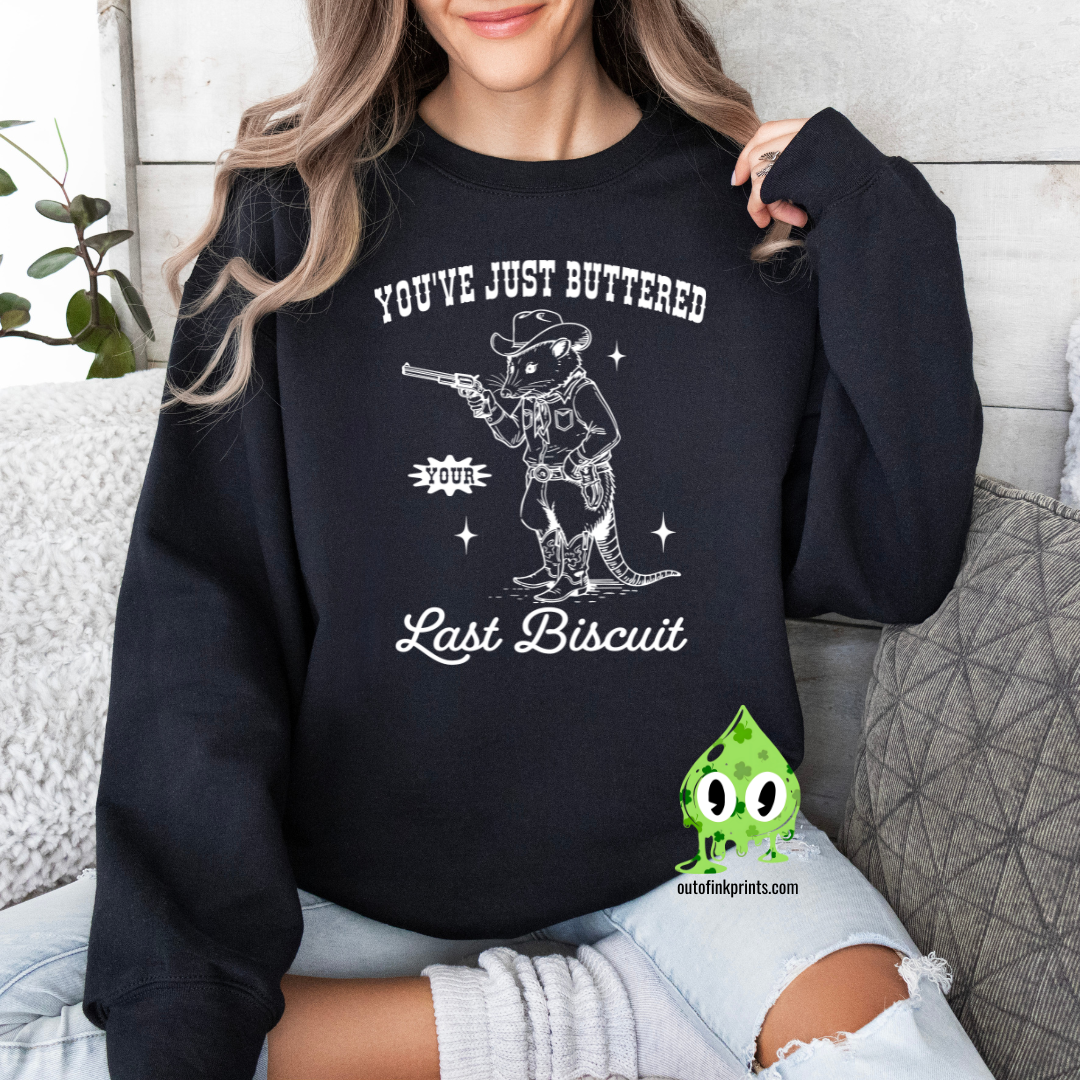 A person wearing a black sweatshirt with the text 'You've Just Buttered Last Biscuit' and an illustration of a mouse holding a gun.