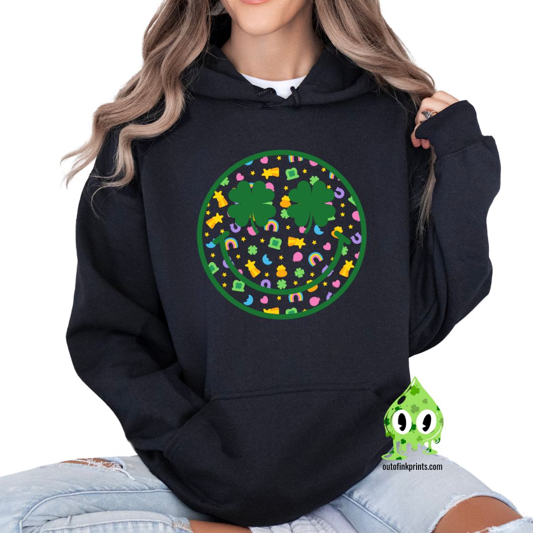 Front view of a black hoodie with a graphic of a smiley face made from clovers and St. Patrick's Day-themed elements.