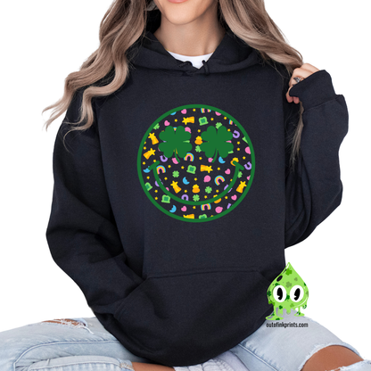 Front view of a black hoodie with a graphic of a smiley face made from clovers and St. Patrick's Day-themed elements.