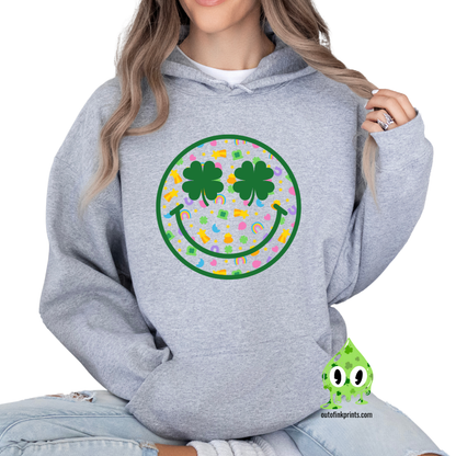Front view of a gray hoodie with a graphic of a smiley face made from clovers and St. Patrick's Day-themed elements.