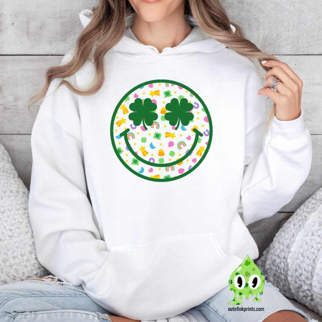 Front view of a white hoodie with a graphic of a smiley face made from clovers and St. Patrick's Day-themed elements.