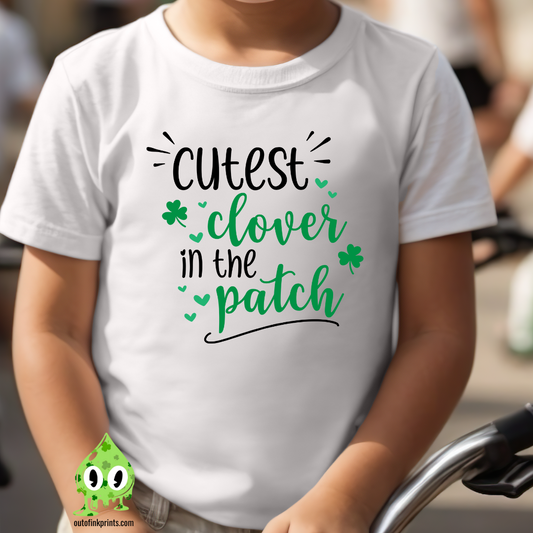 Child wearing a white t-shirt with the text 'CUTEST CLOVER IN THE PATCH' and small clover leaves, in a outdoor setting.