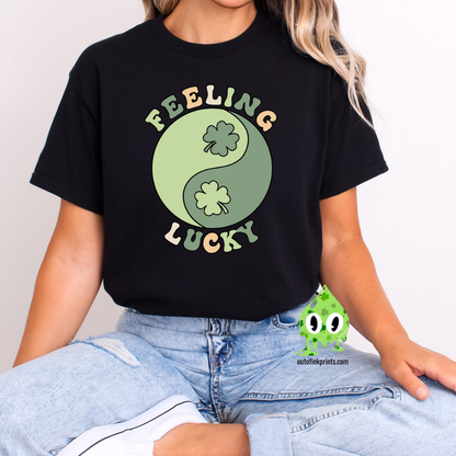 A woman wearing a black  t-shirt with 'Feeling Lucky Yin & Yang' text and shamrock graphics, paired with blue denim jeans.
