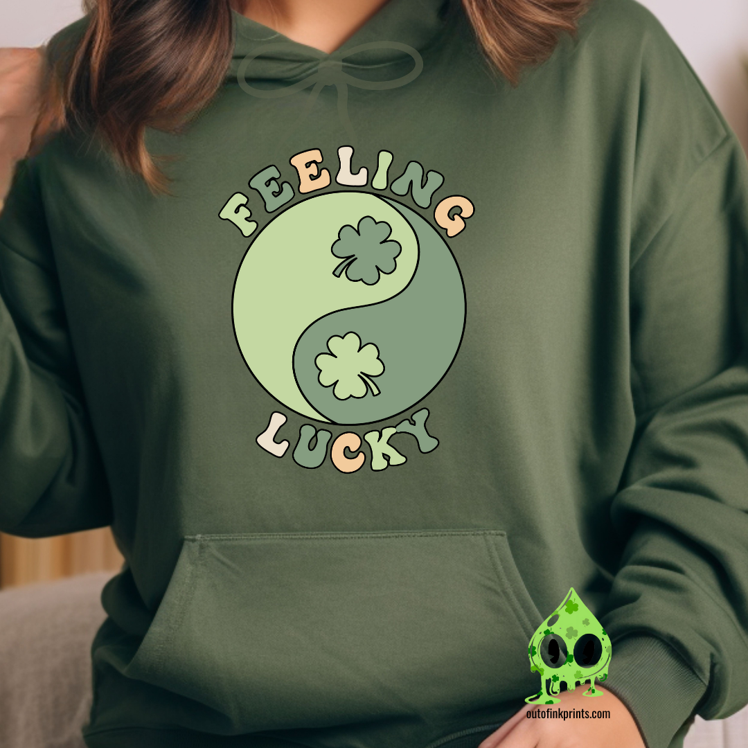 A green hoodie with the text 'FEELING LUCKY' and a graphic of a yin-yang symbol with clovers on both sides.
