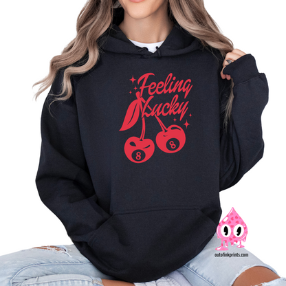 A woman wearing a black hoodie with red text and cherry graphics, posing with one hand on the hoodie 