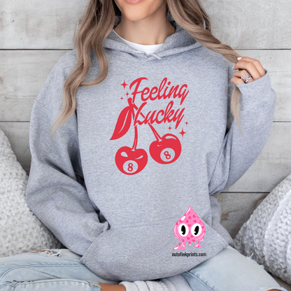 A woman wearing a grey hoodie with red text and cherry graphics, posing with one hand on the hoodie 