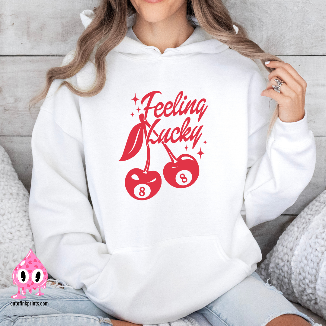 A woman wearing a white hoodie with red text and cherry graphics, posing with one hand on the hoodie 