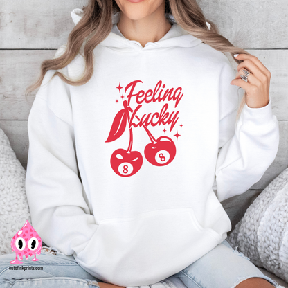 A woman wearing a white hoodie with red text and cherry graphics, posing with one hand on the hoodie 