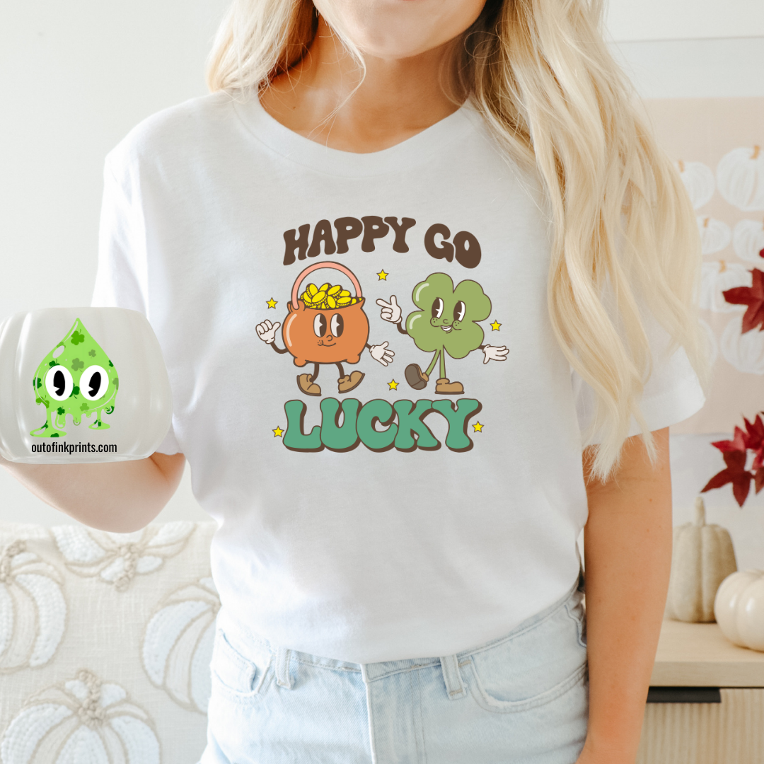 A person wearing a white 'Happy Go Lucky' t-shirt with cartoonish characters and text on it, suitable for St. Patrick's Day celebrations.