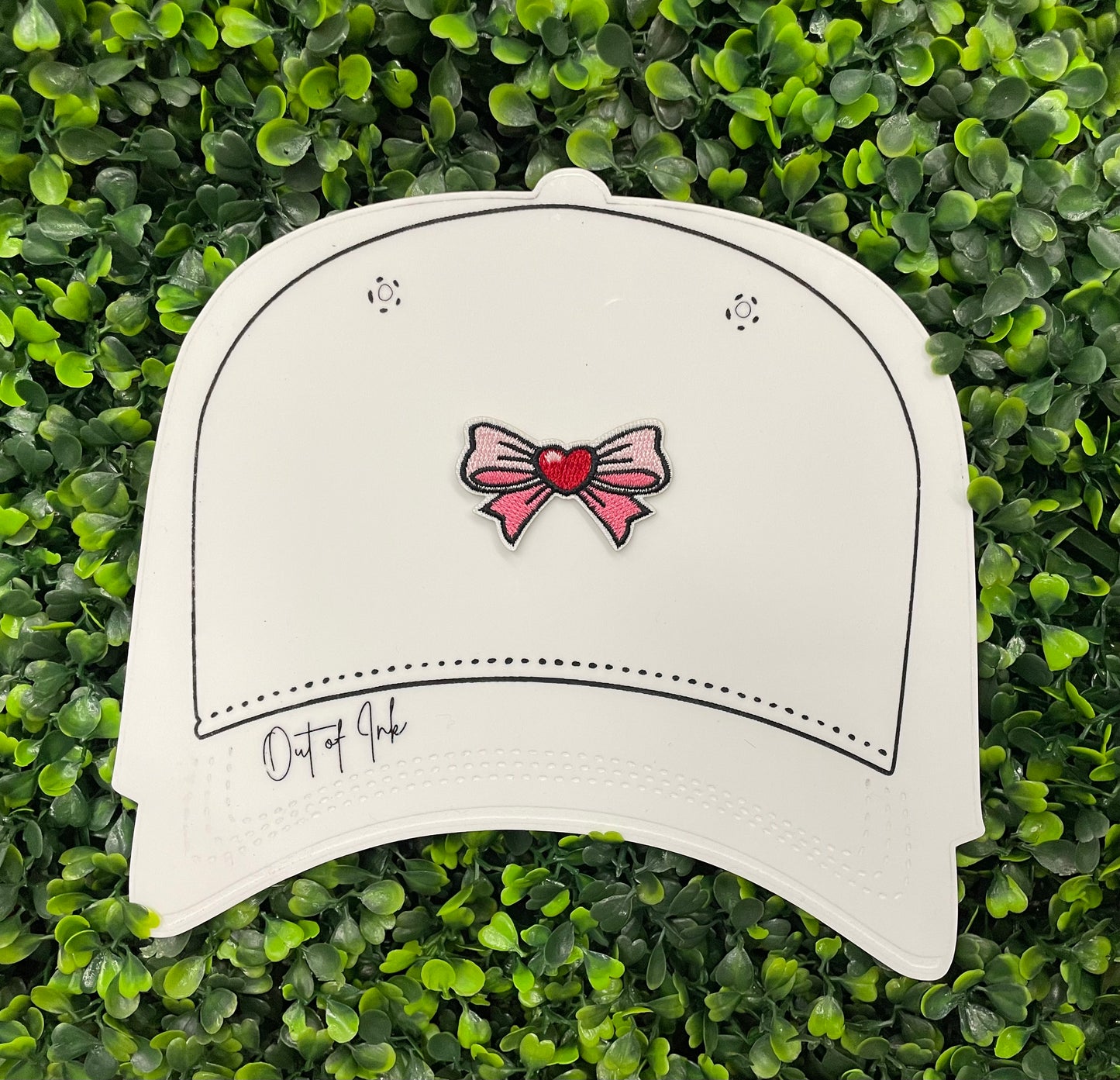 A Bow patch with a heart in the center on a white hat design