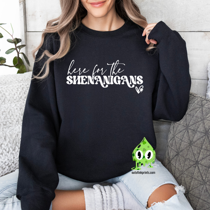 A woman wearing a black sweatshirt with the text 'here for the SHENANIGANS' printed on it.