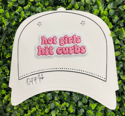 white hat template with an pink embroidered patch that says hot girls hit curbs with a green leafy background. 
