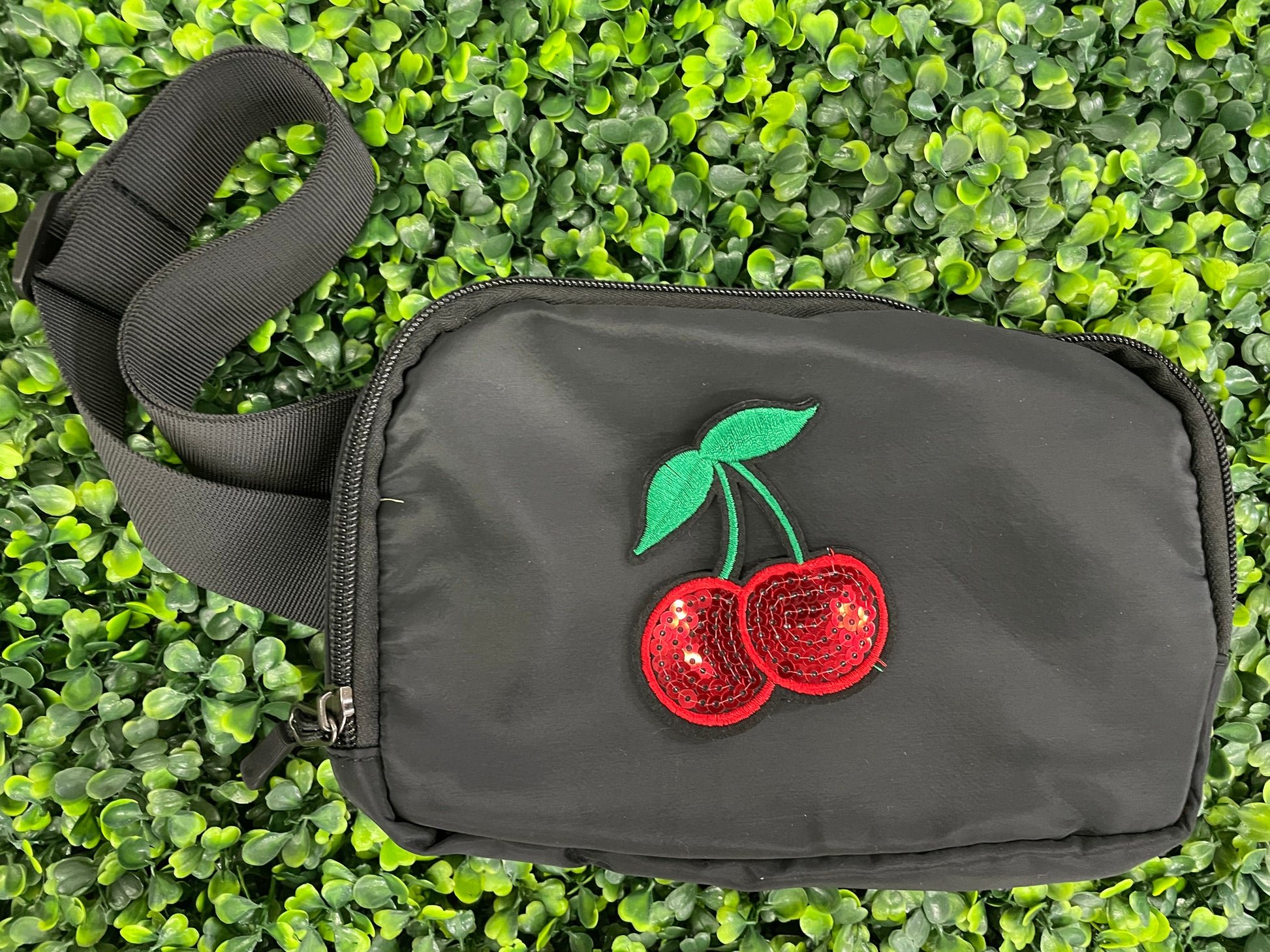  a Sequins cherry patch with a leafy backdrop and a black fanny pack