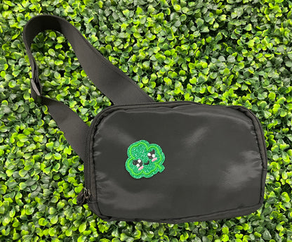 Embroidered patch of a green kawaii clover, placed on a black fanny pack