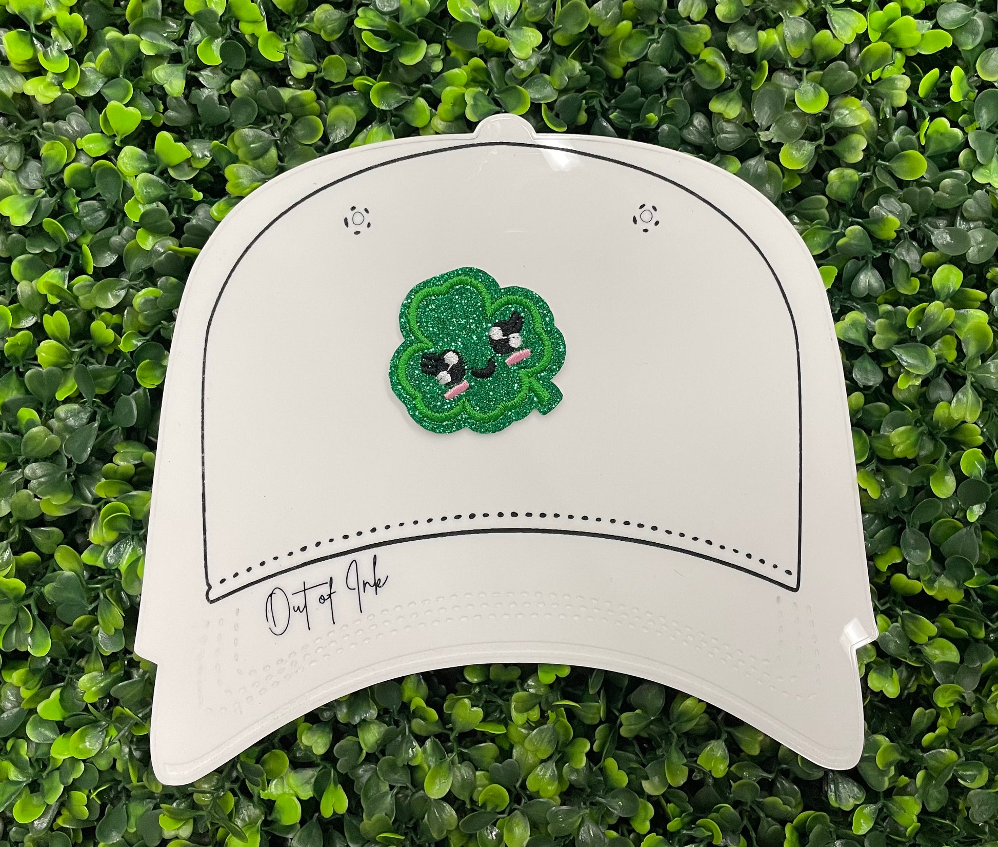 Embroidered patch of a green kawaii clover, placed on a white hat templat