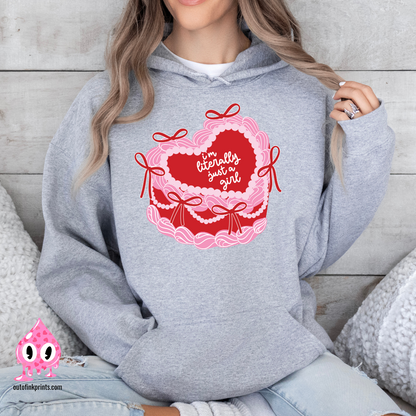 A woman wearing a gray hoodie with a heart and a cake design, featuring the text 'I'm Literally Just a Girl'.
