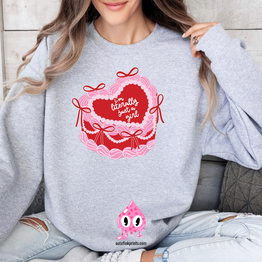 A woman sitting and wearing a gray sweatshirt with a pink heart and text 'I'm Literally Just a Girl', alongside a graphic of a cake.