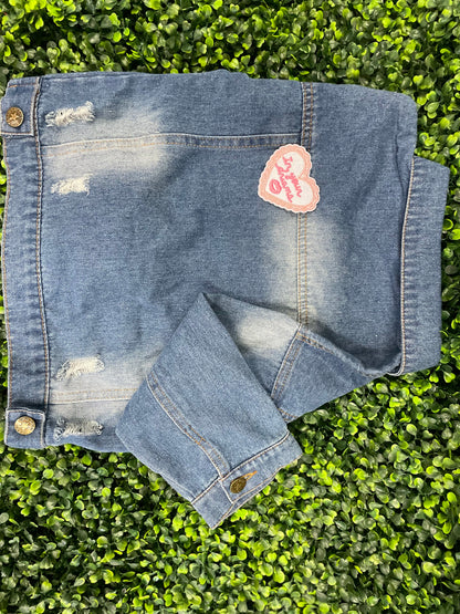 Heart-shaped embroidered patch with 'In your dreams' text held against a children's denim jean jacket