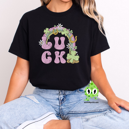 A person wearing a black 'LUCK Rainbow' T-shirt with a checkered pattern and decorative elements such as a four leaf clover and smiley faces.