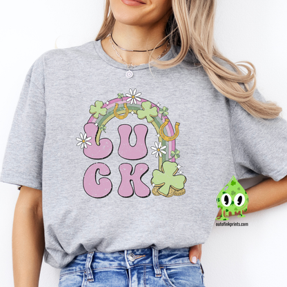 A person wearing a gray  'LUCK Rainbow' T-shirt with a checkered pattern and decorative elements such as a four leaf clover and smiley faces.