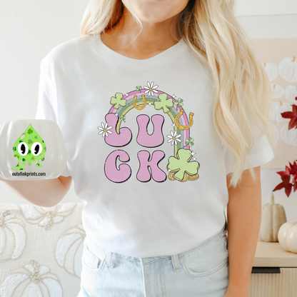 A person wearing a white 'LUCK Rainbow' T-shirt with a checkered pattern and decorative elements such as a four leaf clover and smiley faces.