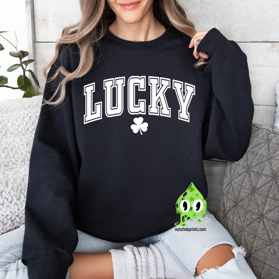 A woman wearing a black sweatshirt with the text 'LUCKY' and a four leaf clover on it, sitting on a couch.
