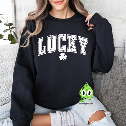 A woman wearing a black sweatshirt with the text 'LUCKY' and a four leaf clover on it, sitting on a couch.