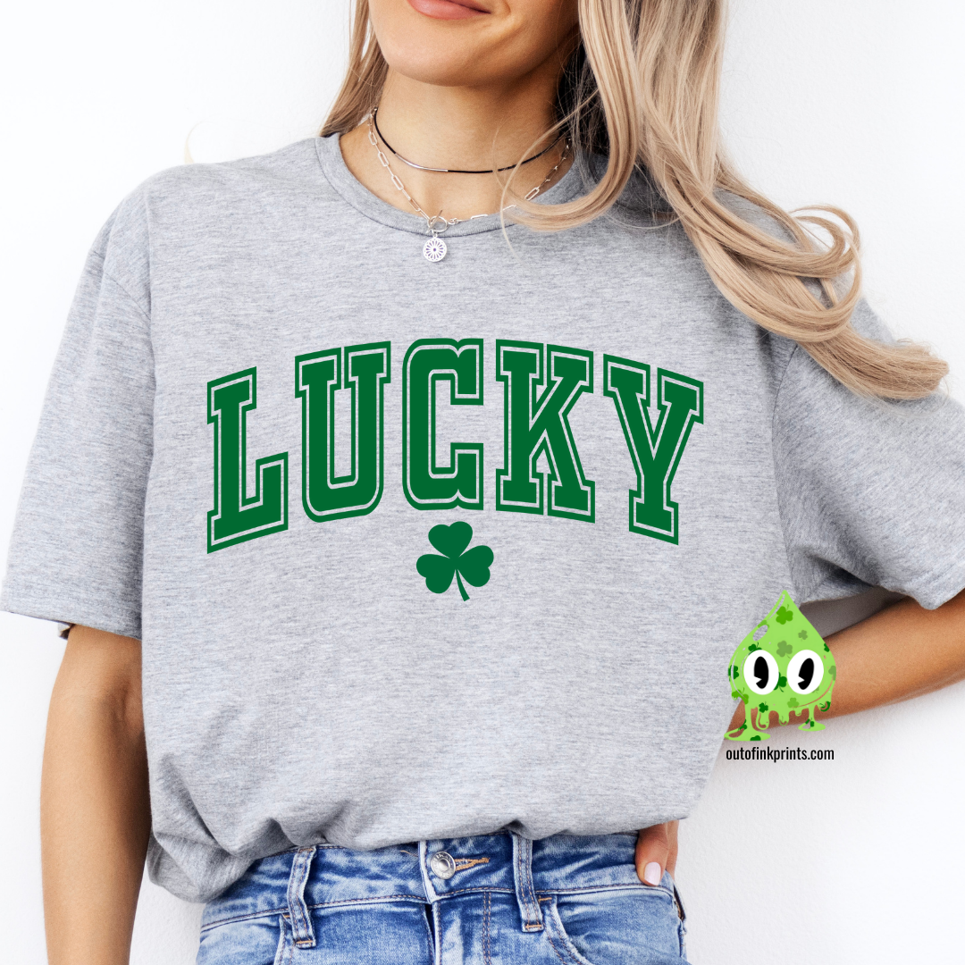 A woman wearing a gray LUCKY Clover T-shirt with a shamrock graphic.