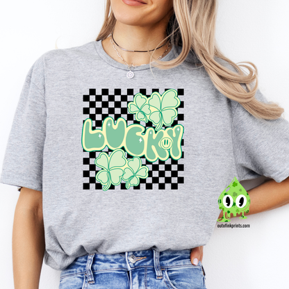 A person wearing a gray 'Lucky Checkered' T-shirt with a checkered pattern and green shamrock graphics, accompanied by the text 'LUCKY!' displayed prominently.
