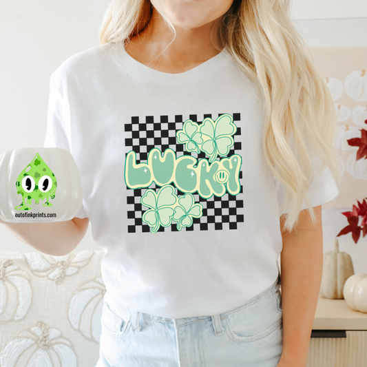 A person wearing a white 'Lucky Checkered' T-shirt with a checkered pattern and green shamrock graphics, accompanied by the text 'LUCKY!' displayed prominently.