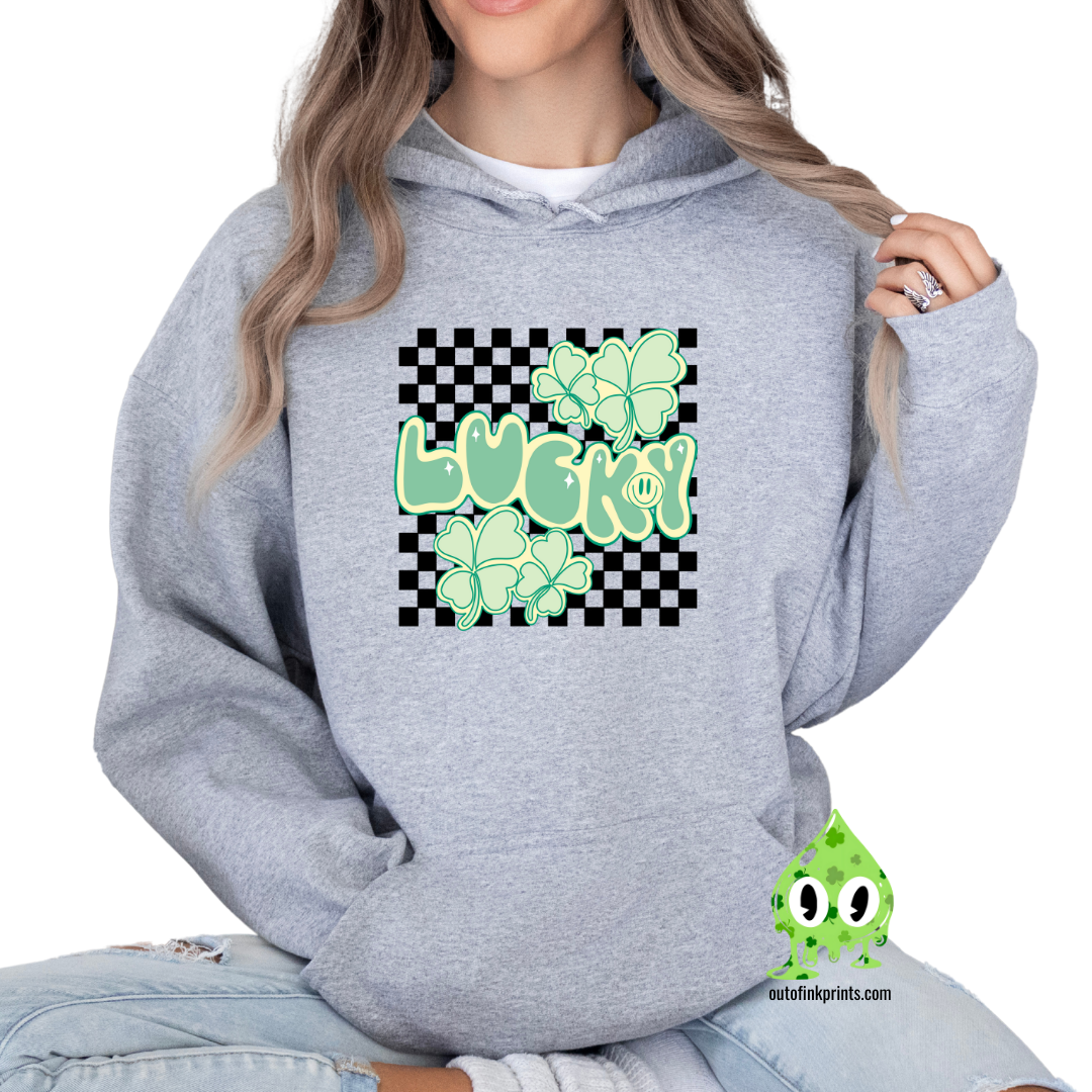 A person wearing a gray hoodie with a checkered pattern and a graphic that includes the text 'LUCKY' and clover designs in green.