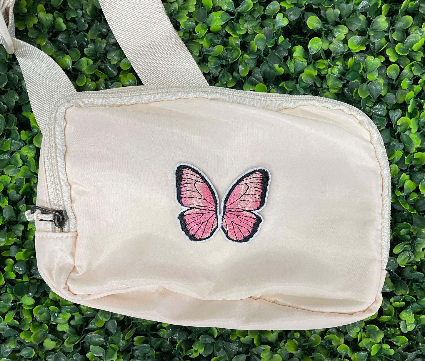 A pink butterfly embroidered patch held onto a white bag