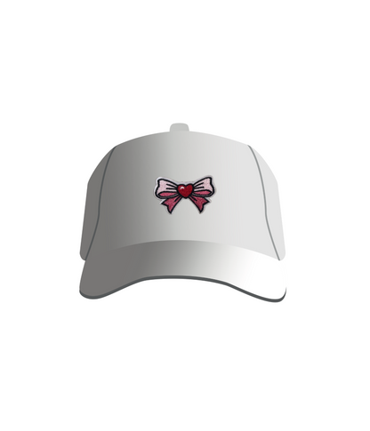 A white baseball cap with a pink bow and red heart embroidered patch on the front.