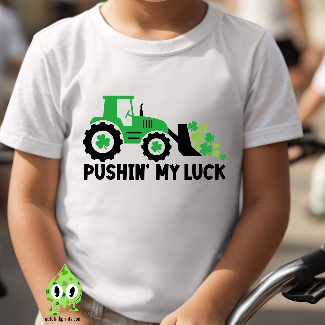 Child wearing a white t-shirt with the text 'PUSHIN' MY LUCK' and a graphic of a tractor and clover.