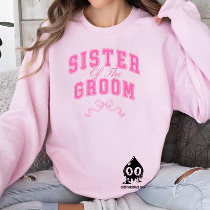 A woman smiling and wearing a pink sweatshirt with 'Sister of the Groom' text and a pink bow design on it.