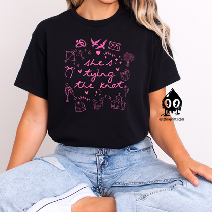 Front view of a black T-shirt with pink text and graphics related to weddings, brides, and bow ties.