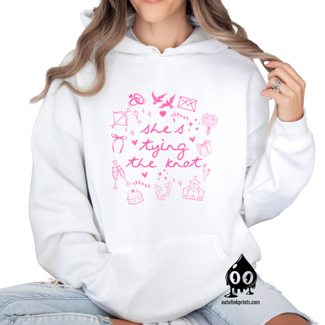 A woman wearing a white hoodie with pink text and graphics related to bridal themes, such as hearts and bows.
