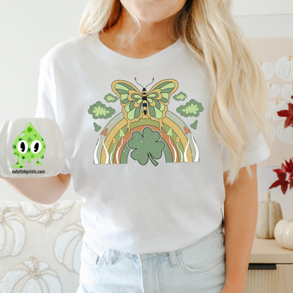 Front view of a white t-shirt with a graphic design of a butterfly and rainbows, predominantly in green color, celebrating St. Patrick's Day.