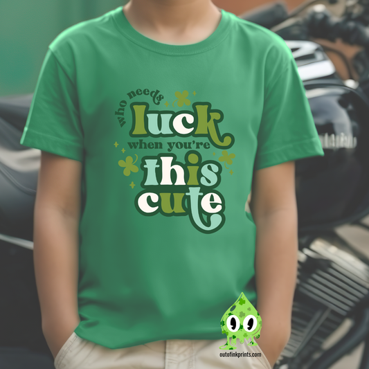 Child wearing a green t-shirt with text 'Who needs luck when you're this cute' and St. Patrick's Day-themed graphics.