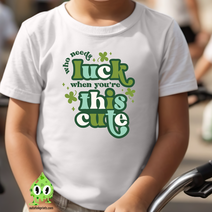 Child wearing a white t-shirt with text 'Who needs luck when you're this cute' and St. Patrick's Day-themed graphics.