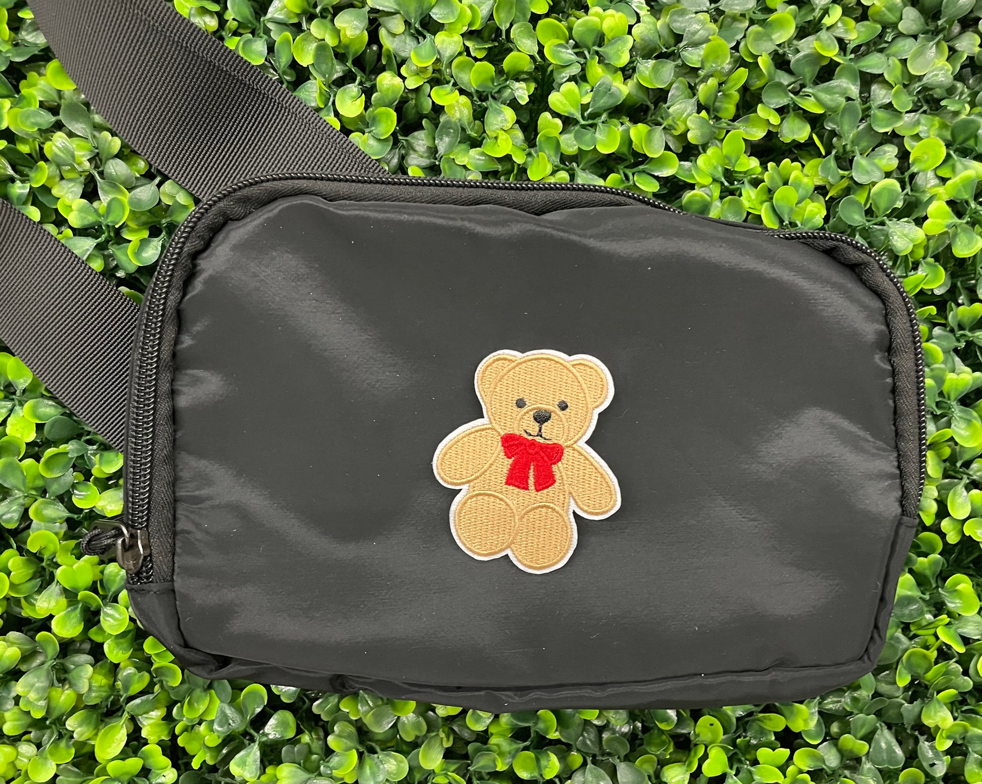 Embroidered Teddy Bear patch with a red bow set on a black shoulder bag