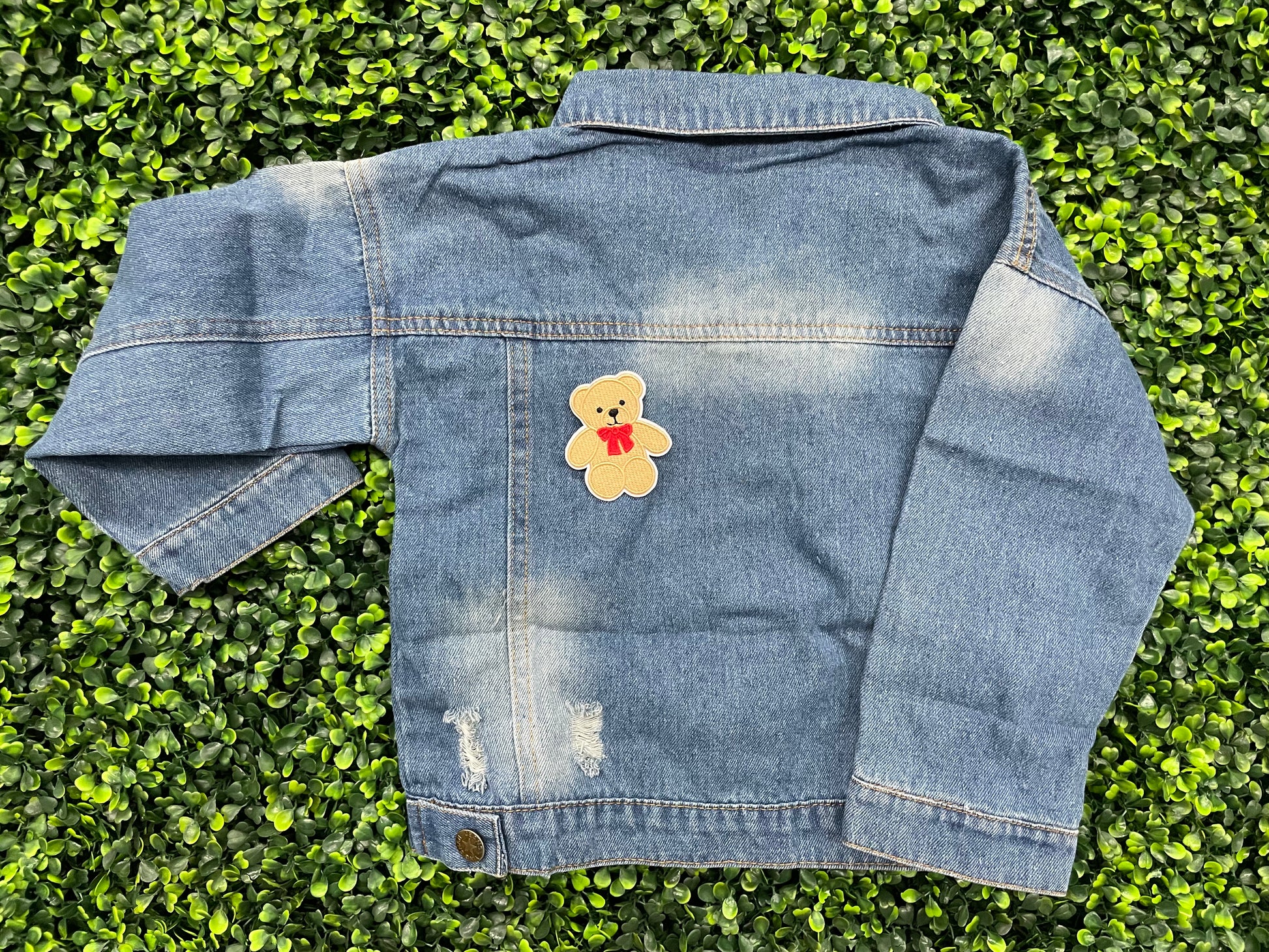 Embroidered Teddy Bear patch with a red bow set on the back of a child's jean jacket